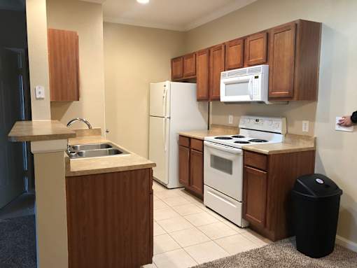A kitchen with white appliances and brown cabinets at Rosemary Apartments, Conroe, TX