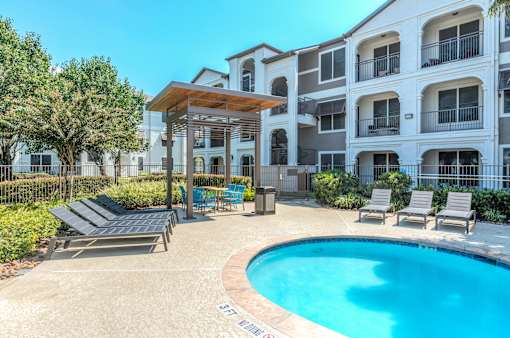 A pool area with a sun lounger and a table at Rosemary Apartments, Texas, 77384