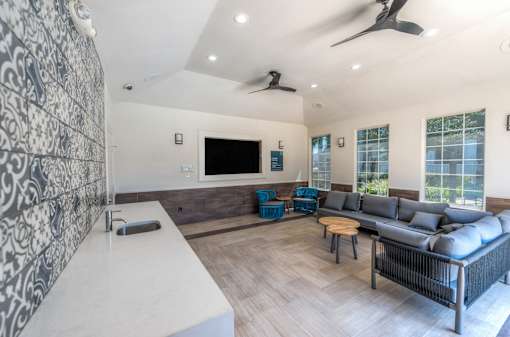 A modern living room with a grey sofa and a patterned wallpaper at Rosemary Apartments, Conroe, TX