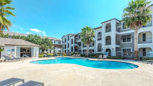 A swimming pool in front of a row of apartment buildings at Rosemary Apartments, Texas