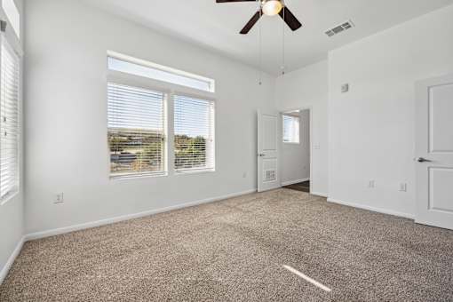an empty living room with carpet and a ceiling fan at Radius on Grove, Austin, 78741