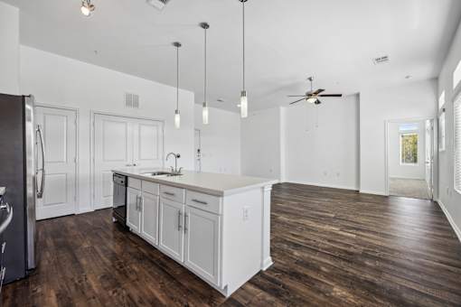 an open kitchen and living room with white walls and wood floors at Radius on Grove, Texas