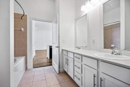 a bathroom with white cabinets and a large mirror and a tub at Radius on Grove, Austin