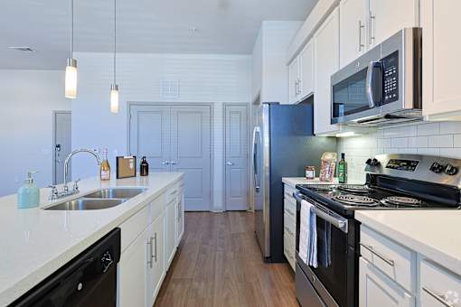 A kitchen with black appliances and white cabinetsat Radius on Grove, Austin, TX
