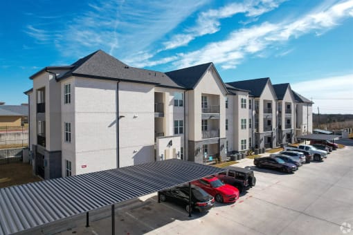 a row of apartment buildings with cars parked in front of them at The Fitzroy San Marcos, Texas