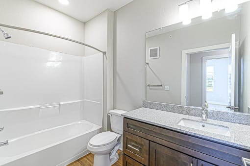 a bathroom with a sink toilet and a mirror at The Fitzroy San Marcos, San Marcos, Texas