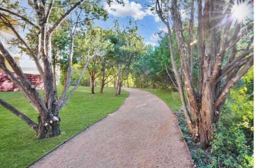 a gravel path through a grassy area with trees on either side at Radius on Grove, Austin, TX, 78741