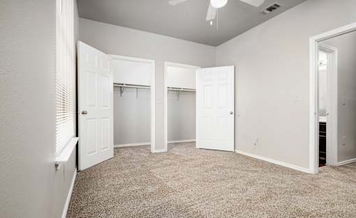 Spacious bedroom with dual closets and carpet at Houston Street Townhomes Apartments, San Antonio, TX