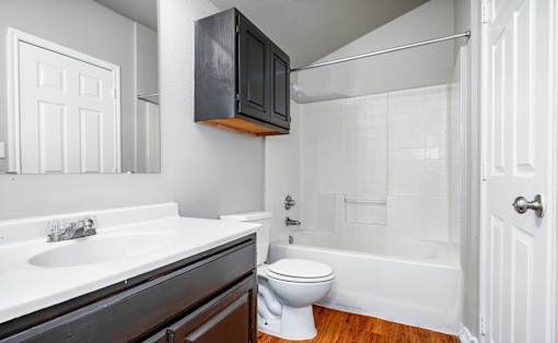 Bathroom with dark vanity and white tile surround at Houston Street Townhomes Apartments, San Antonio, TX 78220