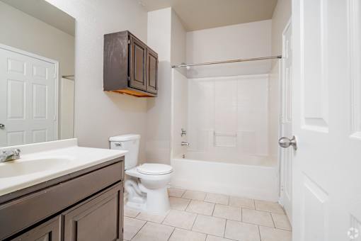 Bathroom with tub and wood cabinets at Houston Street Townhomes Apartments, San Antonio, TX