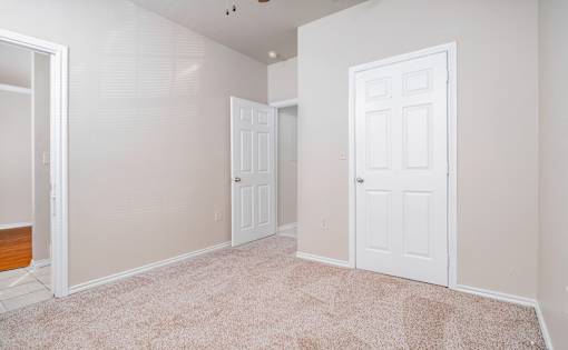 Empty room with carpet and two white doors at Houston Street Townhomes Apartments, San Antonio, 78220