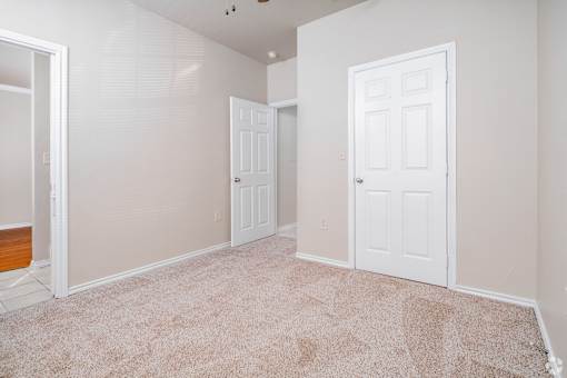 Empty room with beige carpet and white doors at Houston Street Townhomes Apartments, San Antonio, Texas