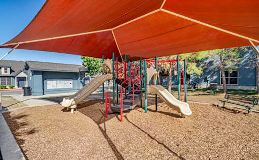 Playground with slides and shade canopy at Houston Street Townhomes Apartments, San Antonio, Texas