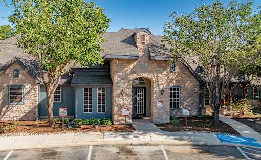 Brick and stone clubhouse exterior with arched entry at Houston Street Townhomes Apartments, Texas, 78220