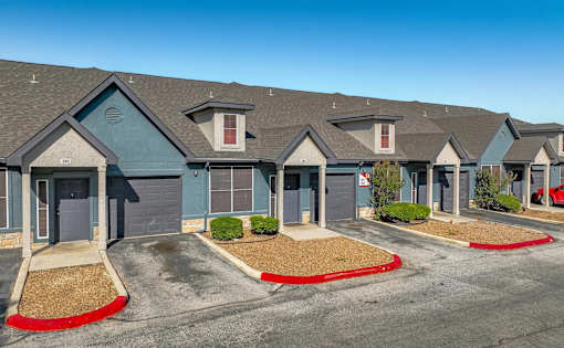 Row of townhome garages with blue and tan facades at Houston Street Townhomes Apartments, Texas