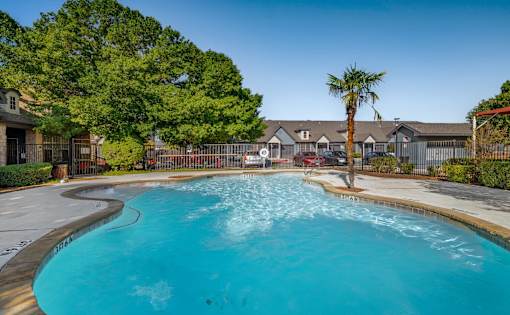 Resort style pool with palm tree and fencing at Houston Street Townhomes Apartments, San Antonio, TX 78220