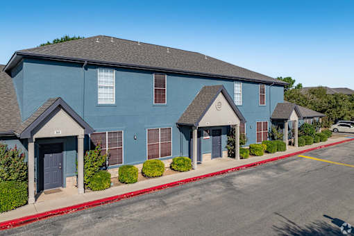 Blue townhome buildings with peaked entry porches at Houston Street Townhomes Apartments, San Antonio, Texas