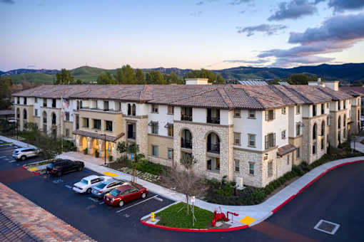 A hotel with a parking lot in front of it.