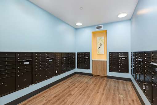 A room with a wooden floor and a row of mailboxes on the wall.