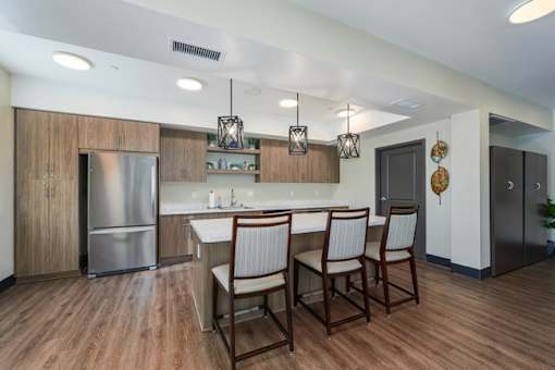 A kitchen with wooden floors and a stainless steel refrigerator.