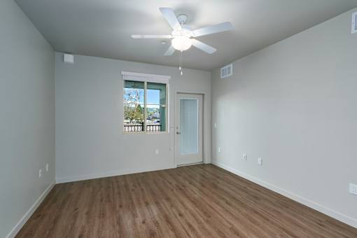 A room with a ceiling fan and wooden flooring.