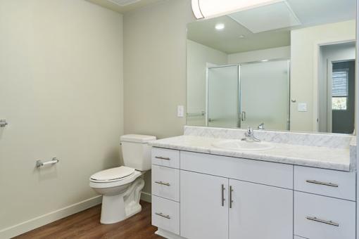 A white bathroom with a toilet, sink, and mirror.