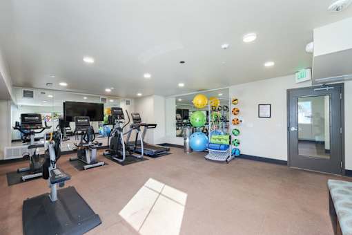 A gym with exercise equipment and a TV.