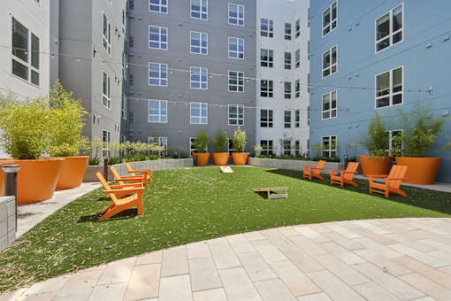 A courtyard with orange chairs and a white bench.