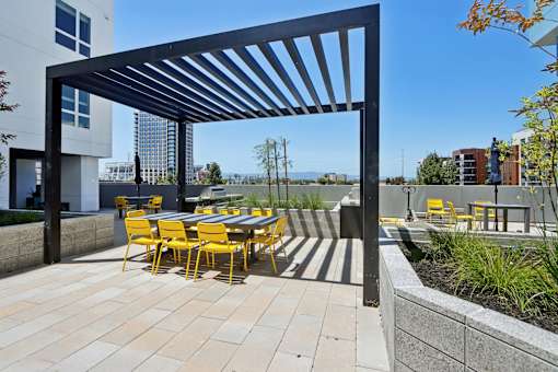 A patio with a table and chairs under a black pergola.