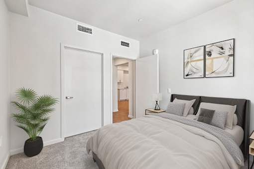 A bedroom with a large bed and a potted plant.