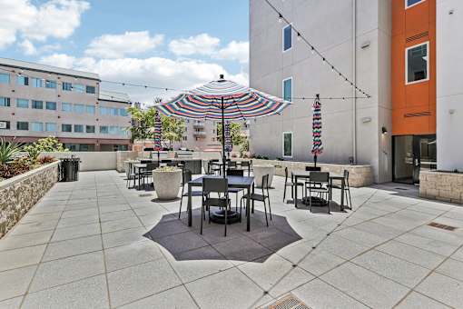 A patio with a table and chairs under a striped umbrella.