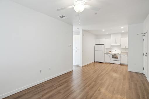 A spacious kitchen and living room with wooden floors and white walls.