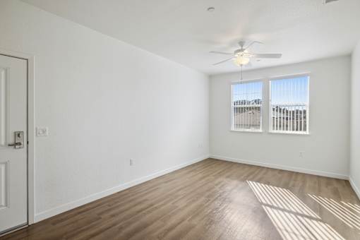 A room with a ceiling fan and a window with blinds.