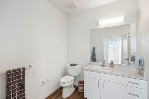 A white bathroom with a toilet, sink, and mirror.