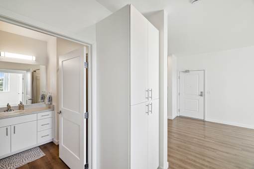 A white bathroom with a sink, mirror, and cabinets.