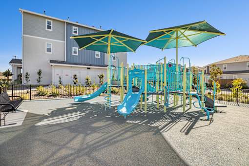 A playground with a blue slide and green umbrellas.