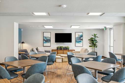 a conference room with tables and chairs and a tv on the wall