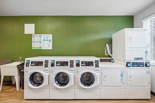 a laundry room with four washer and dryers and a table with a sink