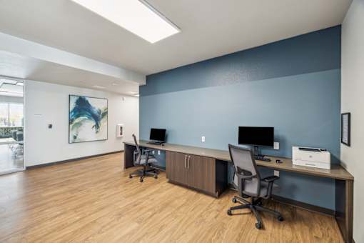 an office with desks and chairs and a blue wall and wood floors