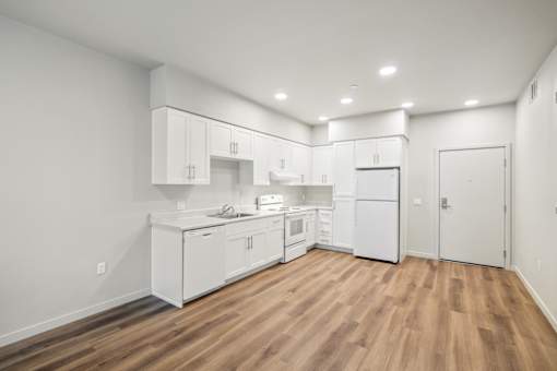 a kitchen with white cabinets and white appliances and a wood floor