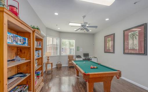 A room with a pool table and a bookshelf.