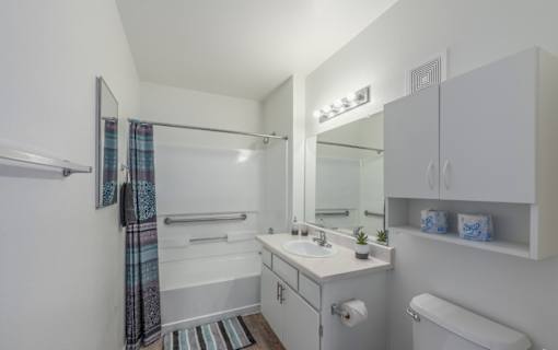 A white bathroom with a toilet, sink, and shower.