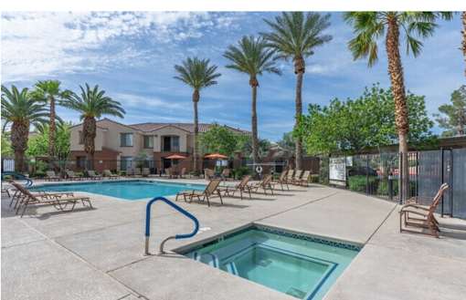 A pool surrounded by palm trees and lounge chairs.