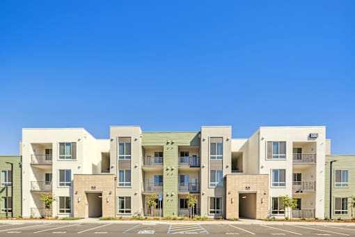 a row of apartments with balconies and a parking lot