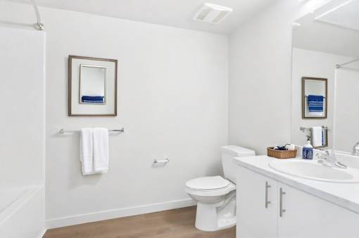 A white bathroom with a toilet, sink, and mirror.