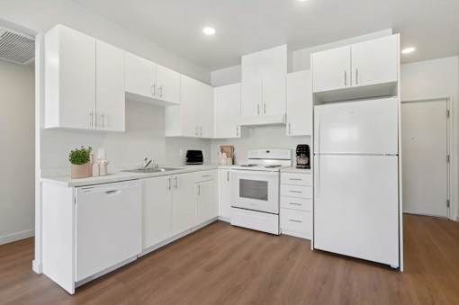 A white kitchen with wooden floors and white appliances.at Mainline North Apartments - Santa Clara, CA, Santa Clara, CA