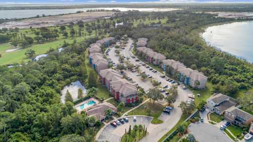 A bird's eye view of a residential area with houses, a swimming pool, and a parking lot.