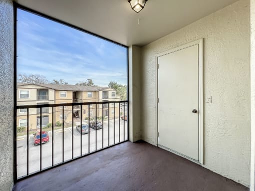 a balcony with a door and a view of a parking lot