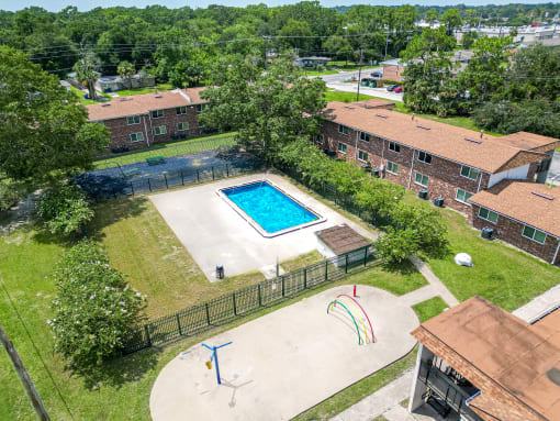 an aerial view of a basketball court and a swimming pool in front of some houses