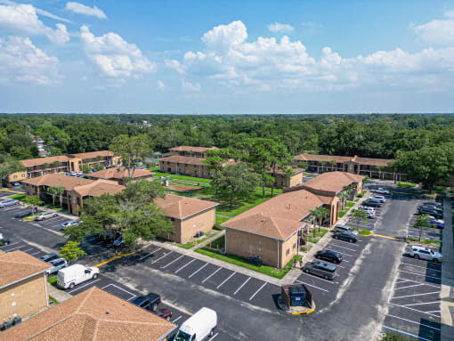 an aerial view of an apartment complex with parking lot and trees